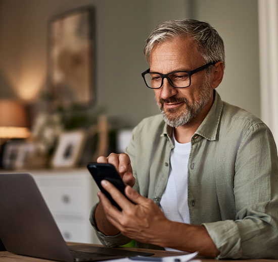 Mann mit Brille telefoniert und macht gleichzeitig Notizen.